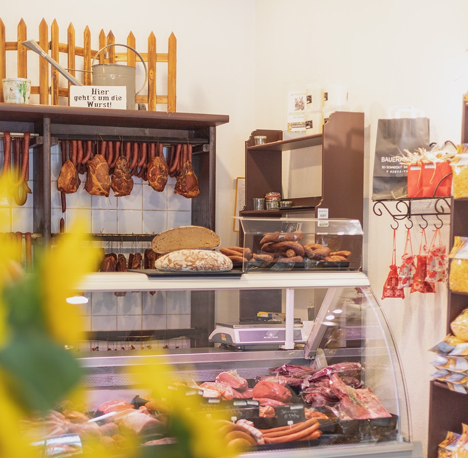 Kind sitzt auf Stroh und hält Ferkel